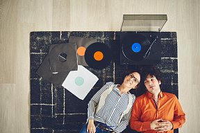 Молодая пара слушает музыкальные записи – иллюстрация необходимости звукопоглощающих решений для обеспечения качественной акустики